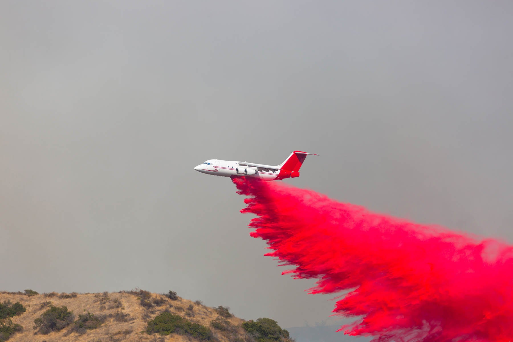 Firefighting plane dropping Phos-check on a hillside